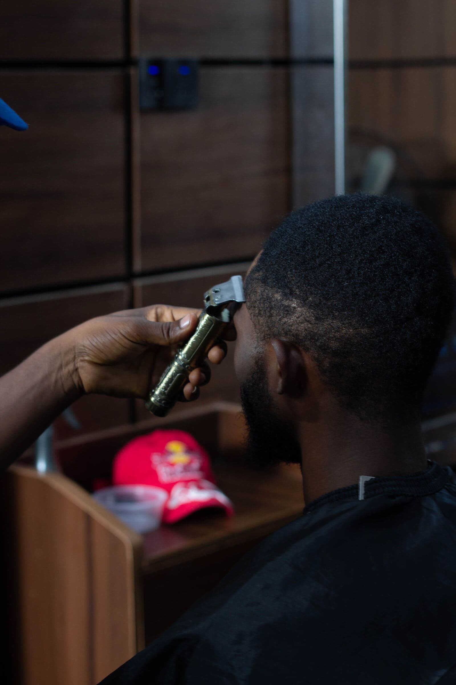 A barber shaping a client's hairline with clippers
